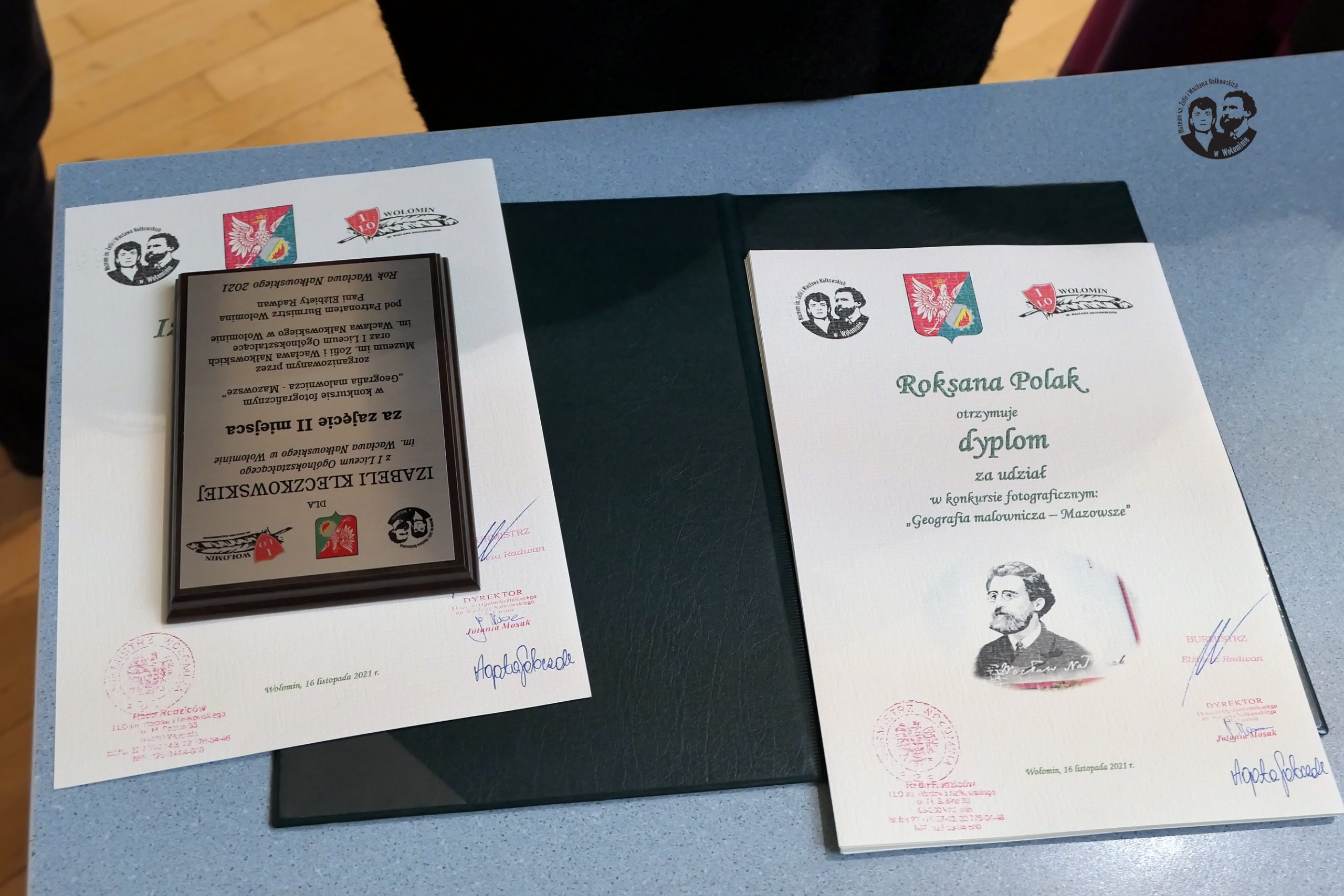 fotografia kolorowa na której widać dyplom za udział w konkursie fotograficznym oraz dyplom i tabliczkę okolicznościowa dla Izabeli Kleczkowskiej