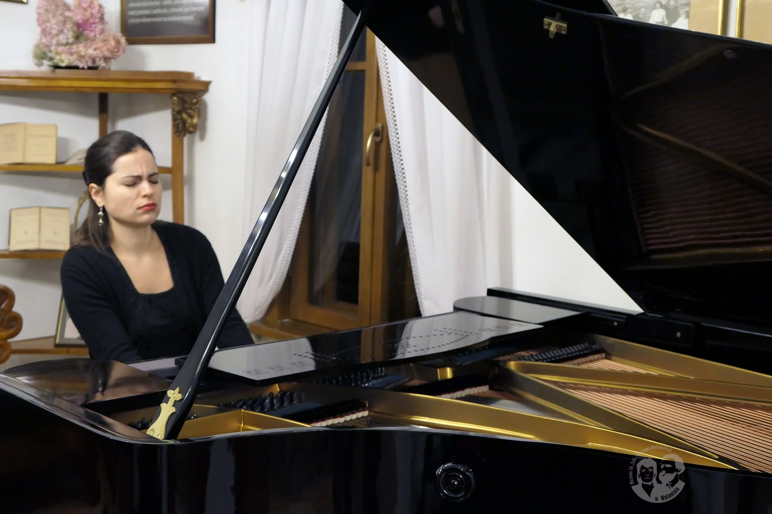 Fotografia kolorowa przedstawiająca pianistkę Weronikę Chodakowską przy fortepianie w czasie gry.