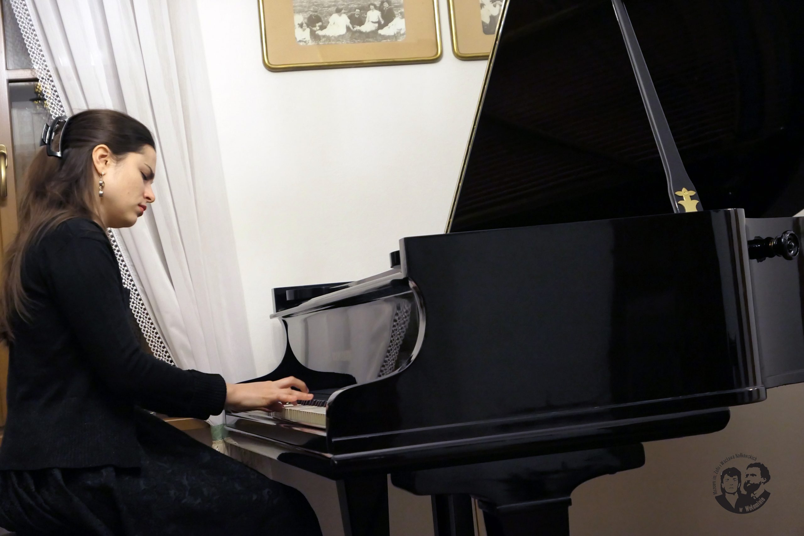 Fotografia kolorowa, pianistka profilem w czasie gry, fortepian widoczny w ujęciu przód/bok.