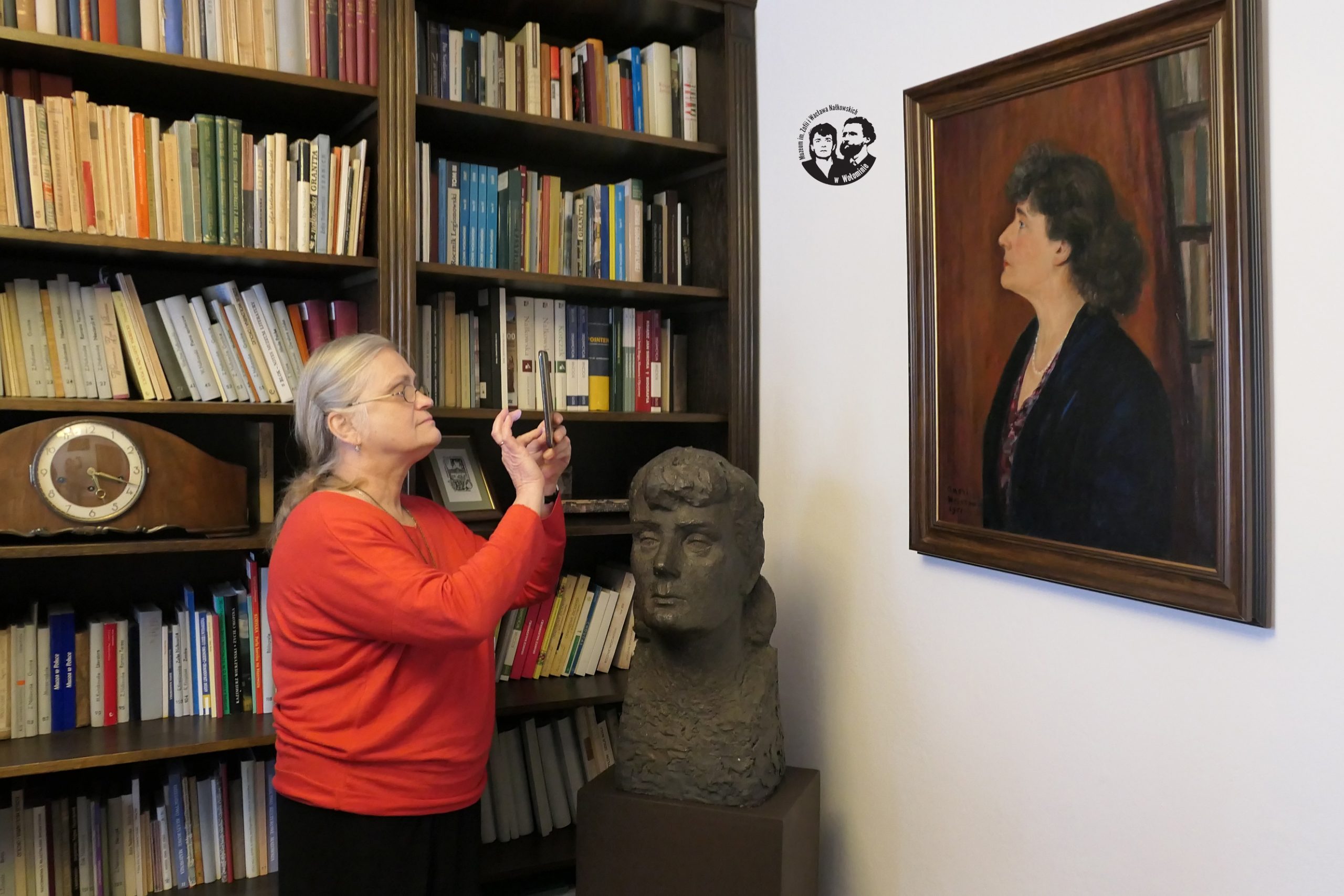 Fotografia kolorowa, sytuacyjna, wykonana w bibliotece muzeum, na zdjęciu prof. dr hab. Maria Jolanta Olszewska robiąca zdjęcie portretu Zofii Nałkowskiej