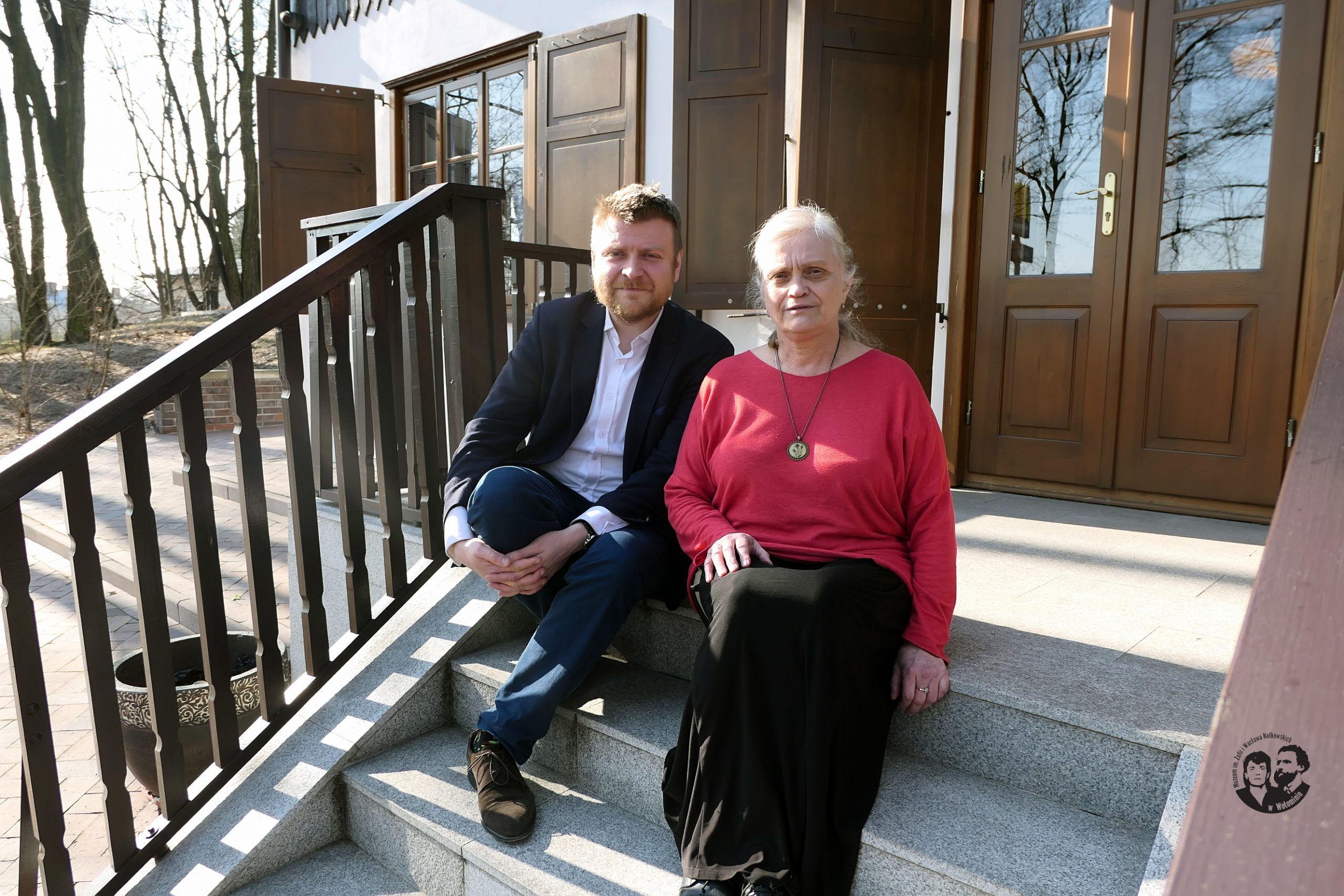 Fotografia kolorowa, sytuacyjna, na schodach przed budynkiem muzeum od strony południowej, na zdjęciu siedzą od lewej dr hab. Karol Samsel, prof. dr hab. Maria Jolanta Olszewska, Krystyna Gostyńska oraz Agata Sobczak